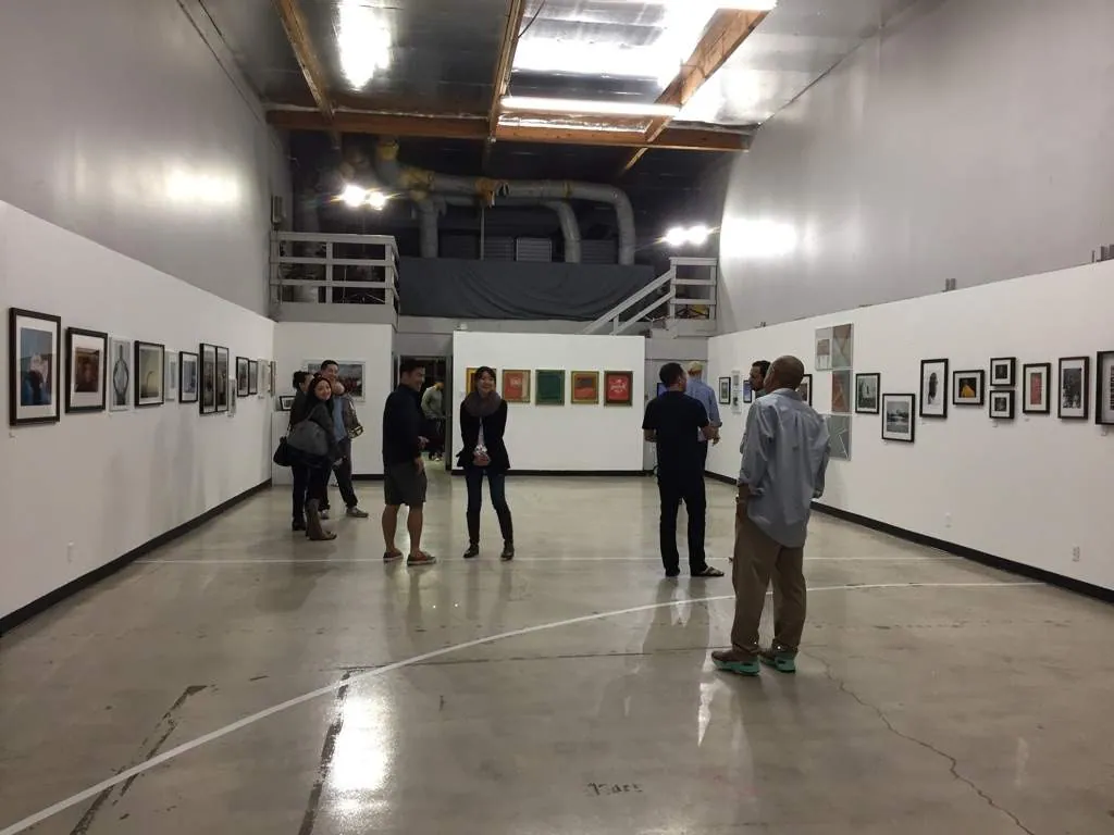 The white gallery room hung salon-style with framed basketball photographs down both long walls, half a dozen visitors standing in the middle of the painted court floor.