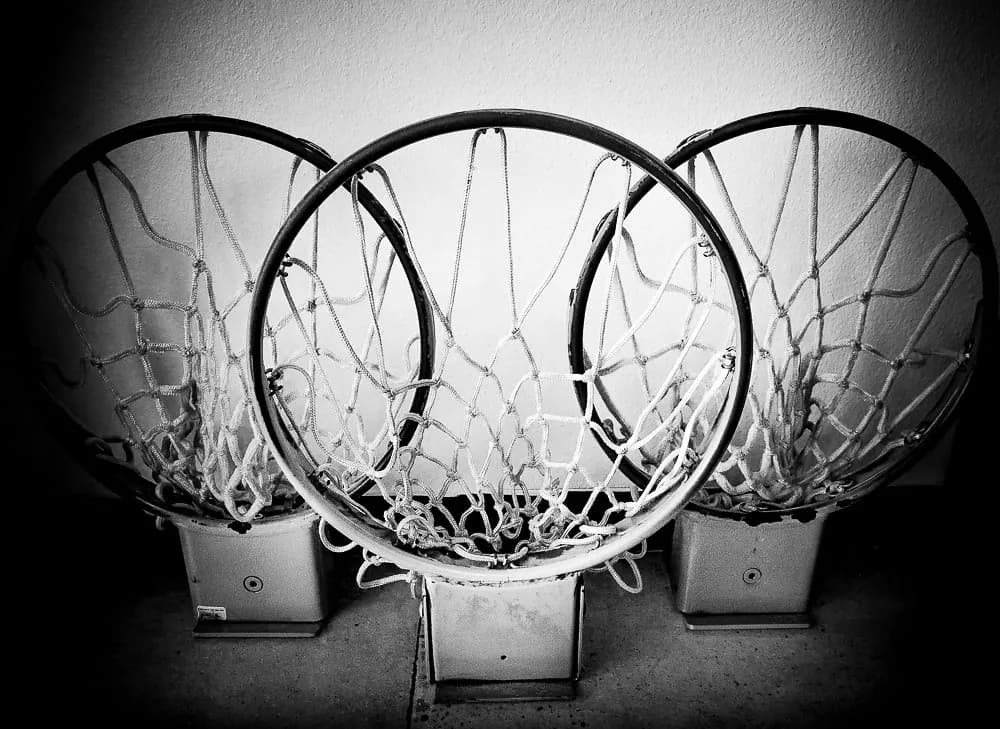 Three basketball rims, still netted, stood side by side against a wall in the shop.