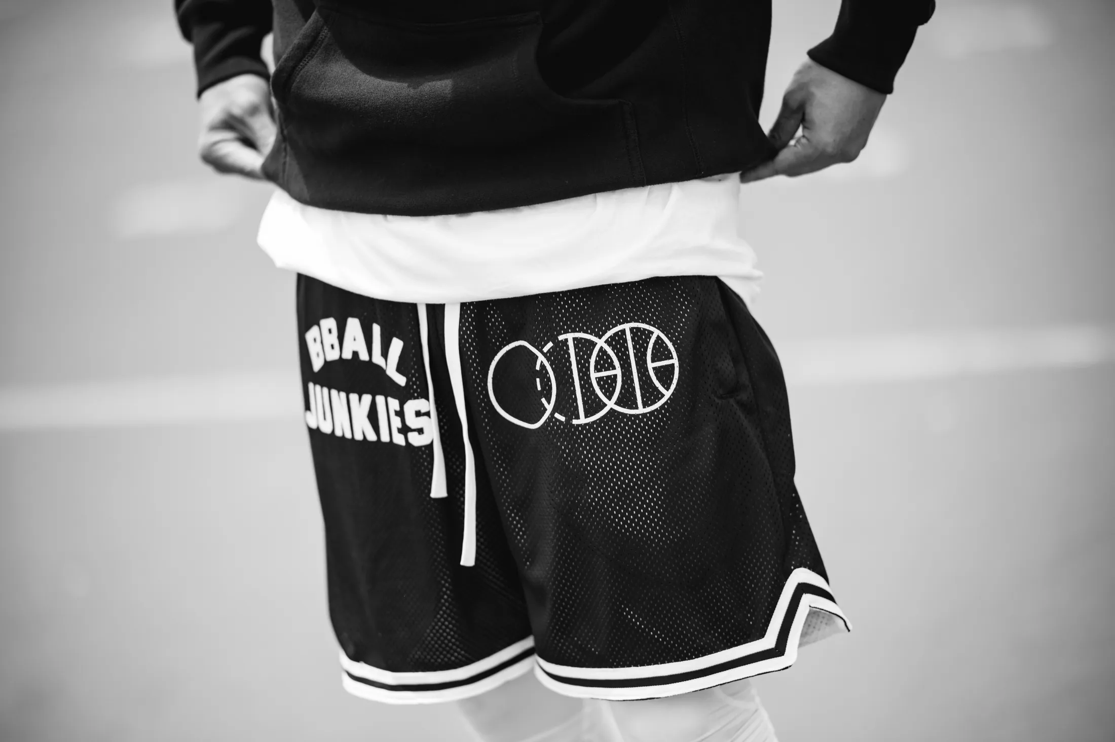 BBALL JUNKIES mesh shorts worn under a black crewneck, the three-ball mark on one leg and the wordmark on the other.