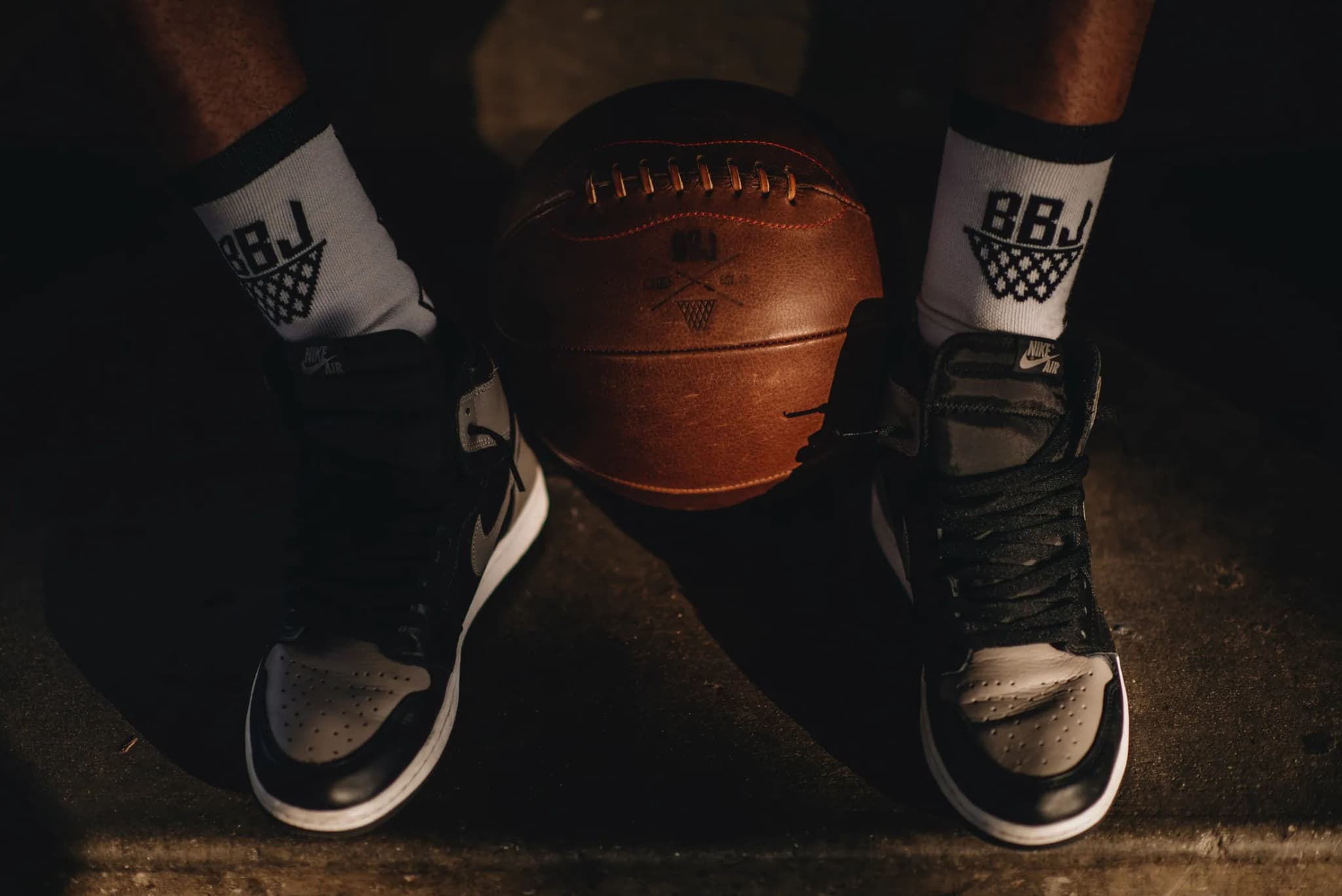 A worn leather ball set down between a pair of high-tops, BBJ crest socks pulled up over the ankles.